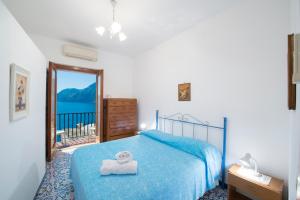 a bedroom with a blue bed and a balcony at Casa Limoncello in Praiano