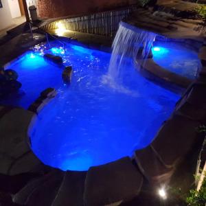 a pool with a waterfall in a backyard at night at Pousada Nossa Senhora Aparecida in Águas de São Pedro