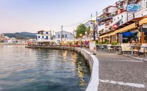 a river in a town with buildings and tables and chairs at Christina Pansion in Kokkari