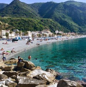a beach with a bunch of people in the water at Hotel Scilla in Scilla