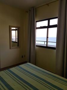 1 dormitorio con cama y ventana con vistas al océano en Caribe Brasileiro a 2 passos da areia, en Arraial do Cabo