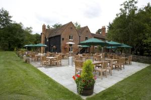 um restaurante com mesas, cadeiras e guarda-sóis em Bartons Mill Pub and Dining em Basingstoke