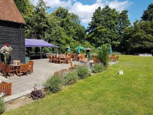 eine Terrasse mit Tischen, Stühlen und Sonnenschirmen in der Unterkunft Bartons Mill Pub and Dining in Basingstoke