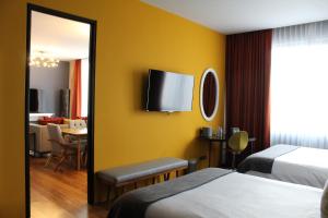 a hotel room with two beds and a tv on the wall at Hotel Love It Consulado in Guadalajara