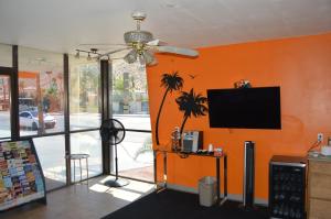a living room with an orange wall with a flat screen tv at Musicland Hotel in Palm Springs