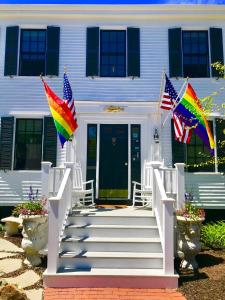 a white house with two flags on the stairs at The Clarendon House in Provincetown