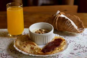 a table with a plate of food and a glass of orange juice at Pousada da Carmem in Visconde De Maua