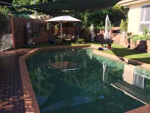 a swimming pool in a backyard with an umbrella at Hideaway on Hillview in Cairns