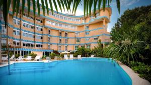a large building with a large swimming pool in front of it at Savoia Hotel Rimini in Rimini
