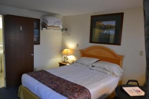 a bedroom with a large bed with white sheets and pillows at The Ship Motel in Alexandria Bay