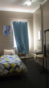 1 dormitorio con cama y cortina azul en Hotel Kerwick, en Redbank