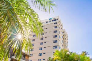 a tall white building with palm trees in front of it at 84 The Spit Holiday Apartments in Mooloolaba
