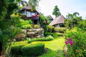 un jardín con una casa y algunas plantas y flores en Chez Piera Resort, en Nakhon Ratchasima