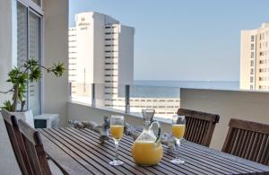a table with two glasses of orange juice on a balcony at 34 Sea Lodge - by Stay in Umhlanga in Durban