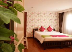 曼谷的住宿－拉查達畢莉斯酒店，一间卧室配有带粉色和绿色枕头的床