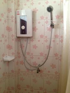 a shower in a bathroom with a dispenser on the wall at Chok-wasana Guest House in Mae Sariang