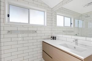 a white bathroom with a sink and two windows at Sanctuary by Sirromet in Mount Cotton