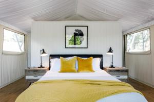 1 dormitorio con 1 cama con almohadas amarillas y 2 ventanas en Sanctuary by Sirromet, en Mount Cotton