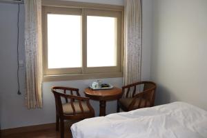 1 dormitorio con mesa, 2 sillas y ventana en Orasung Motel, en Jeju