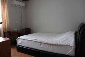 a small bedroom with a bed with white sheets at Orasung Motel in Jeju