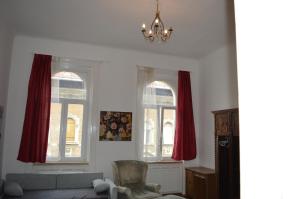 ブダペストにあるFlower Apartmentのリビングルーム(赤いカーテン付きの窓2つ付)