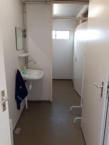 La petite salle de bains est pourvue d'un lavabo et d'un miroir. dans l'établissement B&B boerderij rust, in pipowagens!, à Le Helder