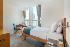 um quarto de hotel com uma cama, uma secretária e uma janela em Summit View Kowloon em Hong Kong