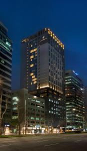 a tall building with lights on in a city at night at L7 Gangnam by LOTTE in Seoul