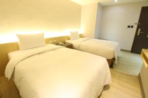 2 camas en una habitación de hotel con sábanas blancas en Simple Life Kaohsiung en Kaohsiung