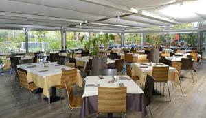un restaurante con mesas y sillas blancas y buscador de mesa en Garda Thermae Village en Arco