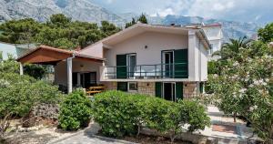 a house with a balcony and mountains in the background at Villa Bandic in Baška Voda