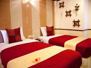 two beds in a hotel room with red and white sheets at Honey House 2 in Bangkok