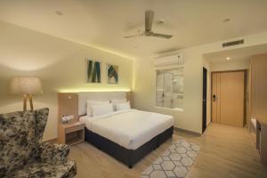 a hotel room with a bed and a chair at 10 Park Street Hotel & Banquets in Gorakhpur