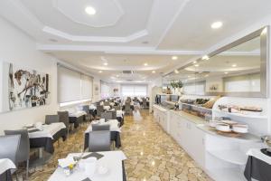 a restaurant with white tables and black chairs at Hotel Bristol in Caorle