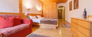 een slaapkamer met een bed en een bank in een kamer bij Hotel Hell in Monguelfo