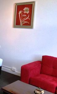 a living room with a red couch and a picture on the wall at Centennial Inn on Bathurst in Launceston