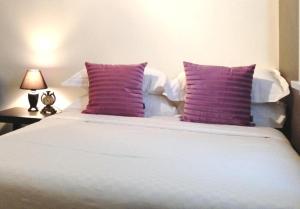 a large white bed with purple pillows on it at Centennial Inn on Bathurst in Launceston