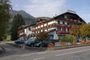 un grand bâtiment avec des voitures garées devant lui dans l'établissement Hotel Torretta, à Bellamonte