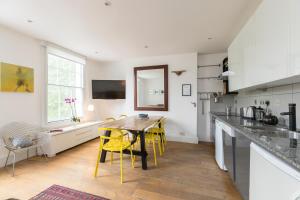 ロンドンにあるALTIDO Spacious & Chic flat in Angelの木製テーブルと黄色い椅子付きのキッチン