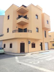 un grand bâtiment jaune avec une voiture garée devant dans l'établissement Calle Eusebio Carballo Estévez, à Corralejo