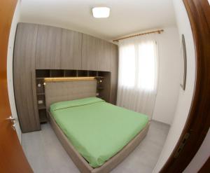 małą sypialnię z zielonym łóżkiem w pokoju w obiekcie Blu Baita w mieście La Maddalena