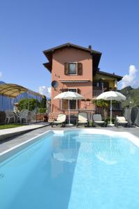 - une piscine avec des chaises et des parasols en face d'une maison dans l'établissement appartamenti Casa Palazzina, à Malcesine