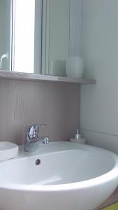 ein weißes Waschbecken in einem Badezimmer mit einem Spiegel in der Unterkunft Mobile Home Cinzia in Pula