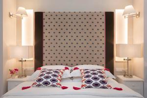a bed with two lamps and a large headboard at Merchant Liston Suite in Corfu