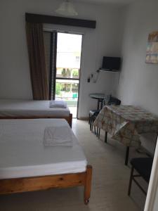 a room with two beds and a table and a window at Thomas Apartments in Kanali +34 photos