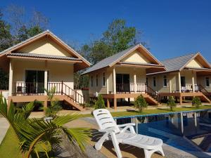 a house with a white chair next to a swimming pool at Poolside Bungalows in Khao Lak