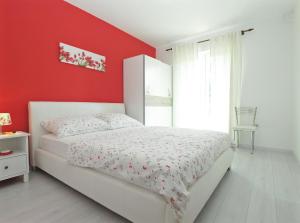 a bedroom with a white bed and red wall at Apartment Vera 1623 in Fažana