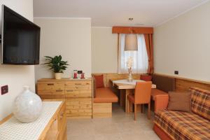 uma sala de estar com um sofá e uma mesa com cadeiras em Residence Marisol Camere & Appartamenti - Mezzana Centre em Mezzana