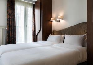 a hotel room with a bed and two lamps at Hôtel Belloy Saint Germain in Paris
