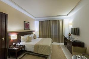 a hotel room with a bed and a desk and a television at Le Corail Suites Hotel in Tunis